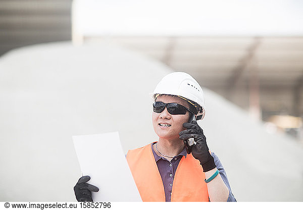 junger Arbeiter in einer Betonfabrik mit Smartphone