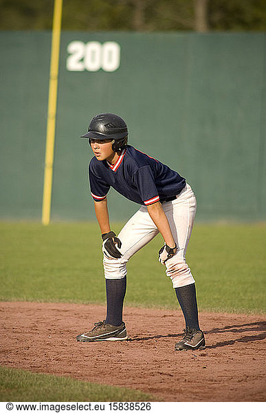 junger Baseballspieler auf dem Base-Pfad mit den Händen auf den Knien