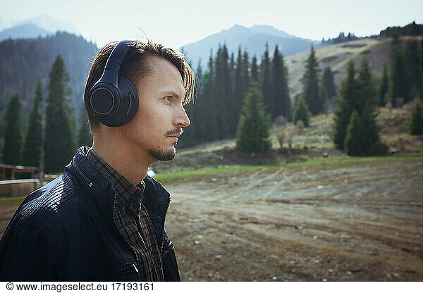 Junger erwachsener Mann im Freien mit Kopfhörern