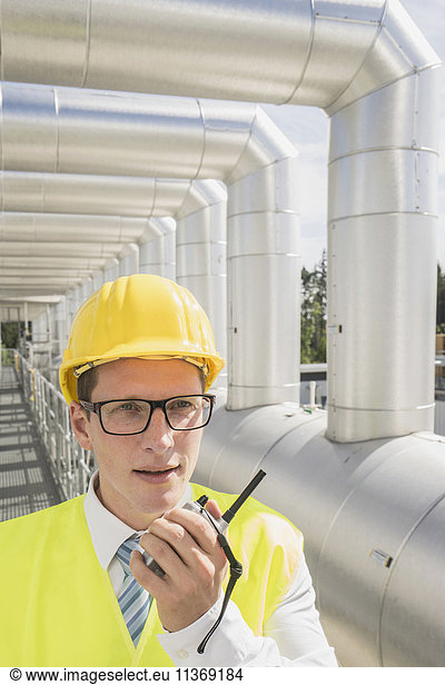 Junger Ingenieur im Gespräch mit Walkie-Talkie in einem geothermischen Kraftwerk