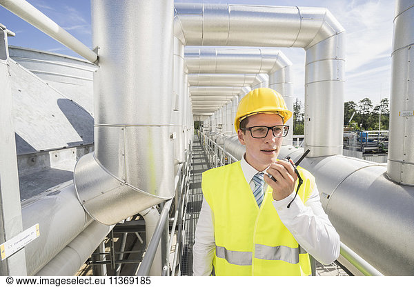 Junger Ingenieur im Gespräch mit Walkie-Talkie in einem geothermischen Kraftwerk
