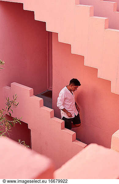 Junger lateinamerikanischer Mann geht die Treppe eines rosa Gebäudes hinunter