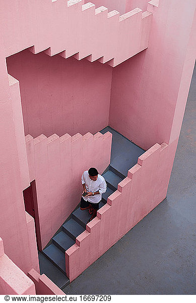 Junger lateinamerikanischer Mann geht die Treppe eines rosa Gebäudes hinunter