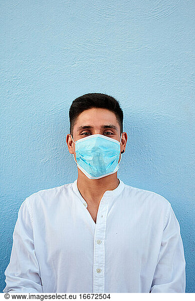 Junger lateinamerikanischer Mann mit Maske auf blauem Hintergrund