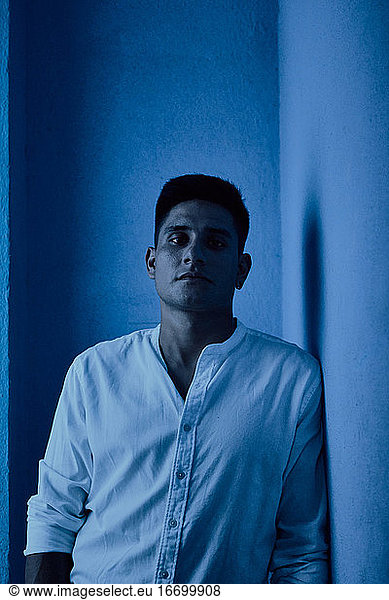 Junger lateinamerikanischer Mann posiert auf blauem Hintergrund