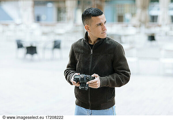 Junger männlicher Fotograf mit Kamera  der wegschaut