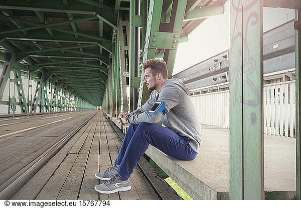 Junger männlicher Läufer  der sich auf dem Bahnsteig einer S-Bahn-Station ausruht