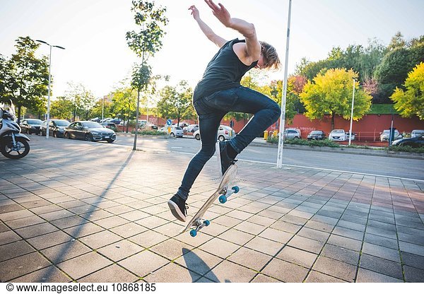 Junger männlicher Skateboarder beim Skateboarden auf dem Bürgersteig