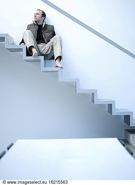 Junger Mann auf einer Treppe sitzend  tiefer Blickwinkel