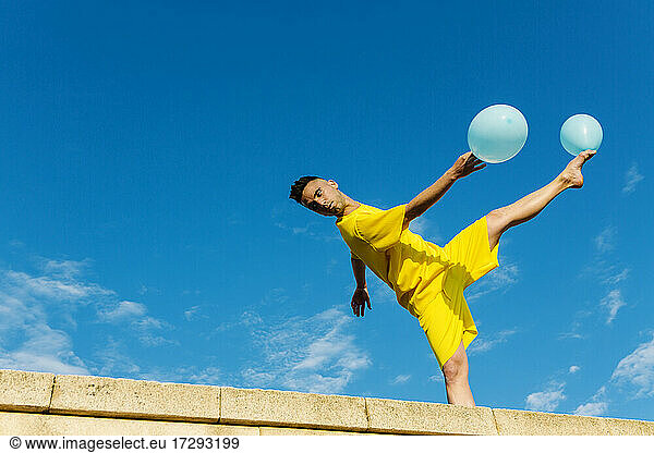 Junger Mann balanciert beim Tanzen mit Luftballons