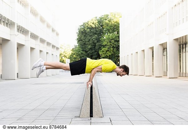 Junger Mann balanciert horizontal auf Trennwand