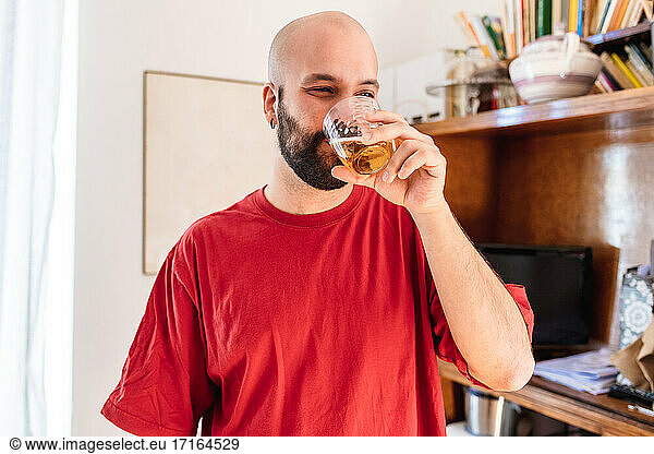 Junger Mann bei einem Drink zu Hause