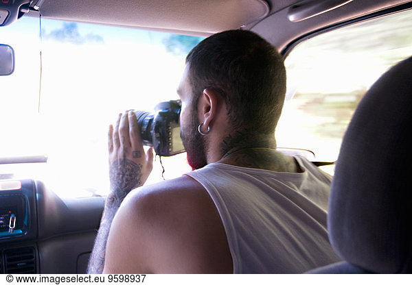 Junger Mann beim Fotografieren durch die Autoscheibe