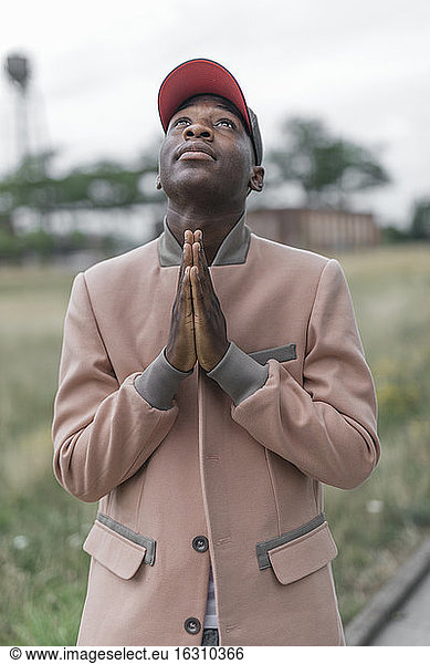 Junger Mann betet mit religiösem Glauben im Freien stehend