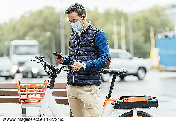 Junger Mann  der ein Mobiltelefon benutzt  während er auf der Straße in der Stadt steht  während COVID-19