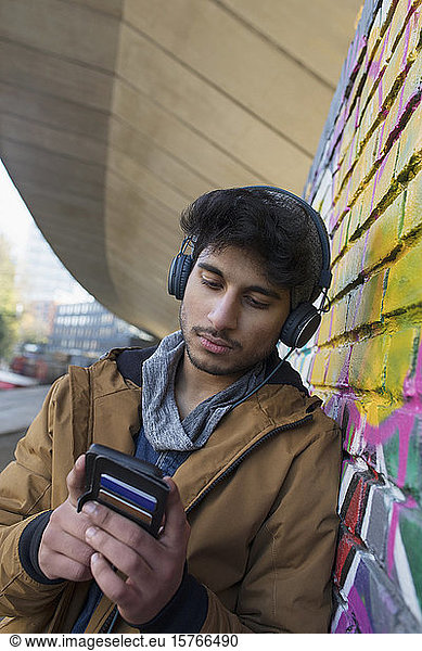 Junger Mann  der mit Kopfhörern und mp3-Player Musik hört
