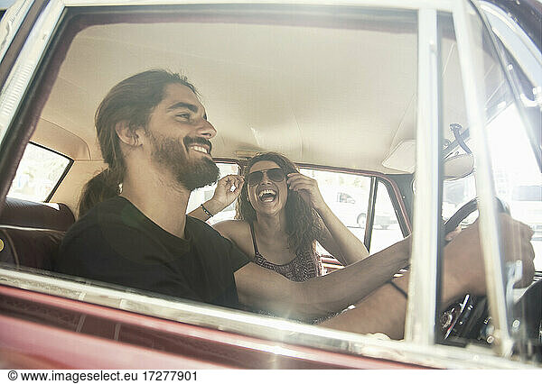 Junger Mann fährt Auto mit junger Freundin an einem sonnigen Tag