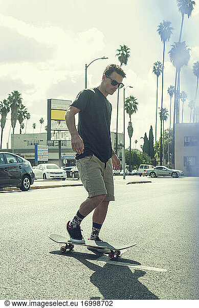 Junger Mann fährt Skateboard auf der Straße in der Stadt