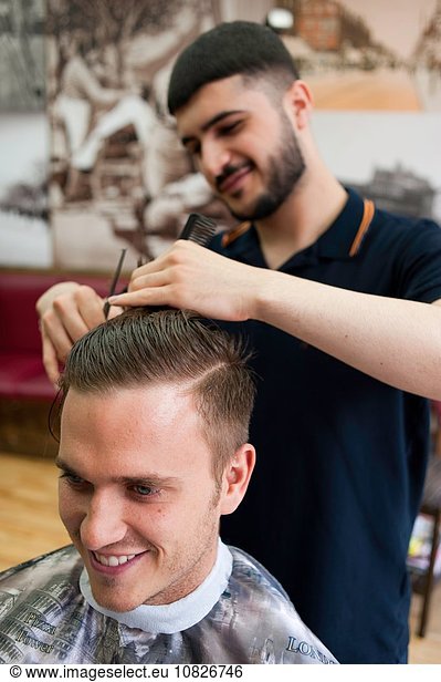 Junger Mann im Friseurladen mit Haarschnitt  lächelnd