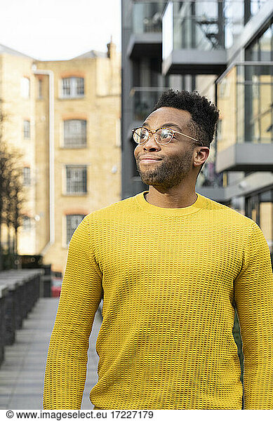 Junger Mann im gelben Pullover schaut weg