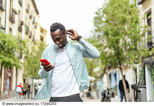 Junger Mann in Freizeitkleidung benutzt sein Smartphone auf der Straße
