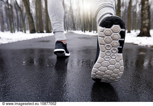 Junger Mann joggt durch verschneiten Wald  niedriger Schnitt  Rückansicht