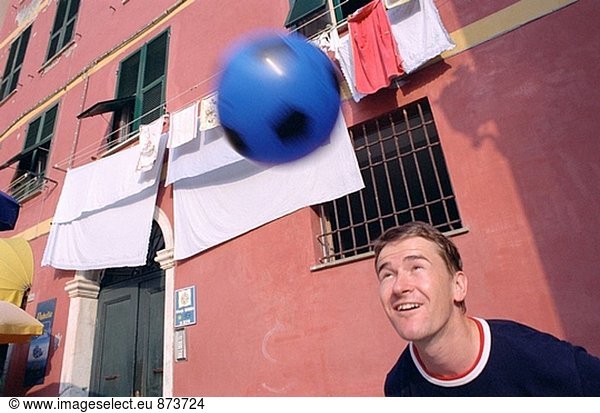 Junger Mann Köpfe blau Soccer Ball an Kleidung hanging out in Mitte der Stadt  Trocknen Vernazza  Terre  Italien