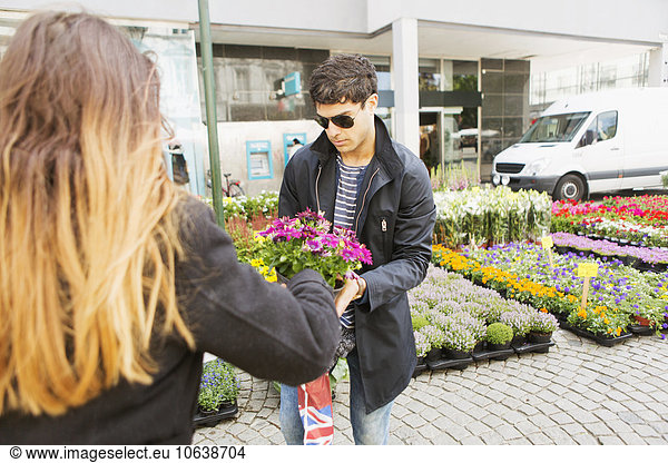 Junger Mann kauft Blumentöpfe von einer Verkäuferin
