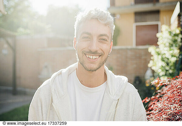 Junger Mann lächelnd im Hinterhof