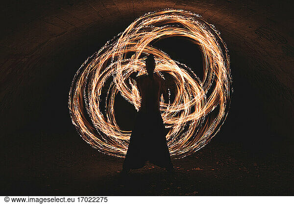 Junger Mann mit Feuerring im dunklen Tunnel