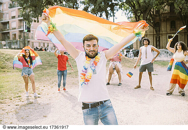 Junger Mann mit Flagge bei Pride-Event im Park