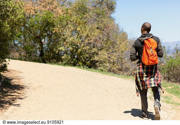 Junger Mann mit Rucksack beim Spaziergang im Park