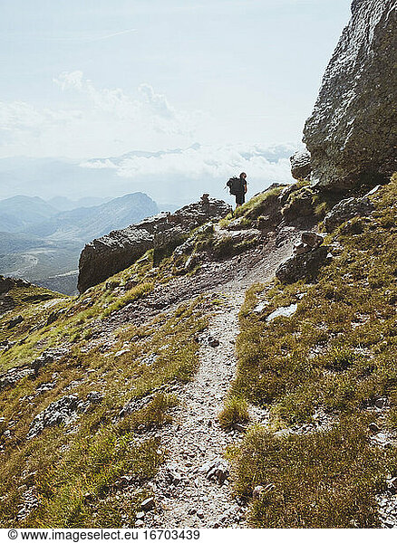 Junger Mann mit Rucksack blickt auf sein Ziel beim Klettern  den Gipfel