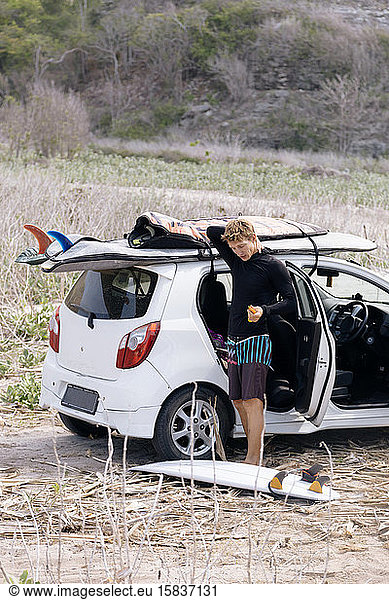 Junger Mann mit Surfbrett in der Nähe des Autos