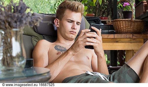 Junger Mann  nutzt die Technik seines Mobiltelefons auf der Terrasse im