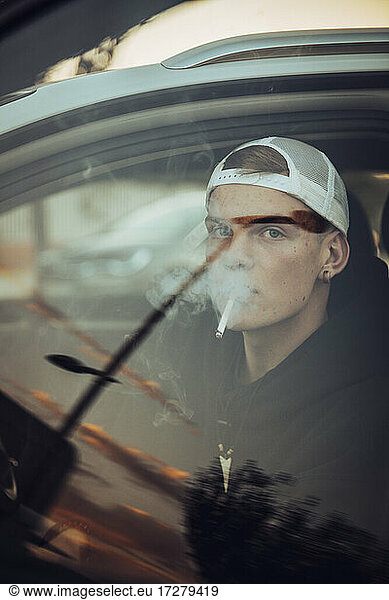 Junger Mann raucht Zigarette in Auto sen durch Fenster