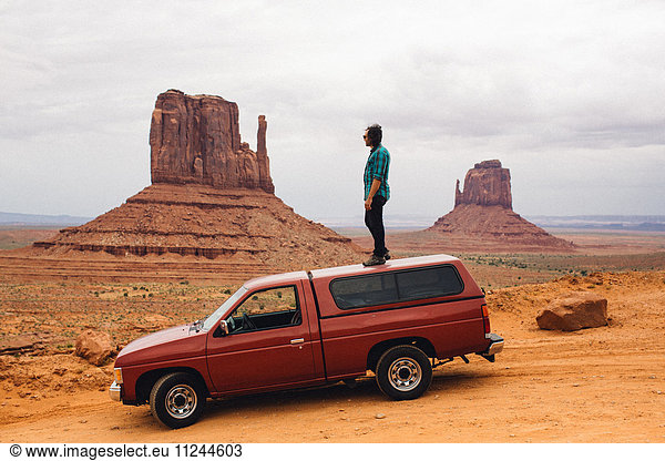 Junger Mann schaut von der Spitze des Allradantriebs hinaus  Monument Valley  Arizona  USA