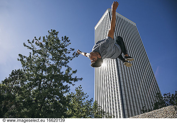 Junger Mann springt beim Parkour gegen den Torre Picasso in der Stadt