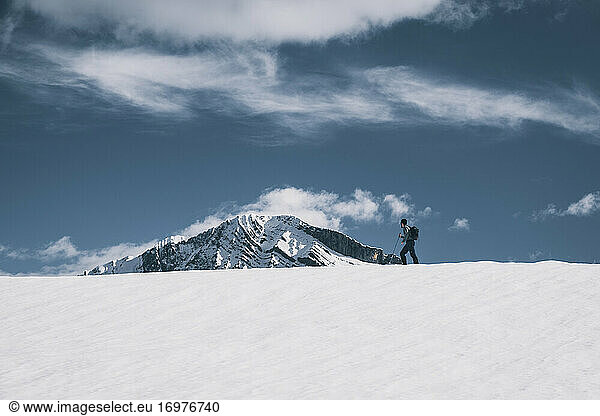 Junger Mann starrt auf einen schneebedeckten Berg  während er über einen verschneiten Bergrücken wandert