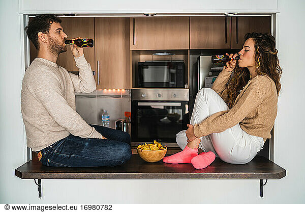 Junger Mann und Frau trinken Bier und essen Chips