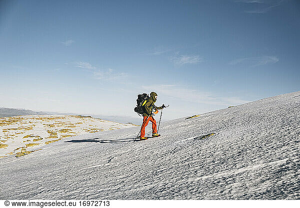 Junger Mann wandert bergauf auf Schnee gegen einen klaren blauen Himmel  Gredos  Avila  Spanien