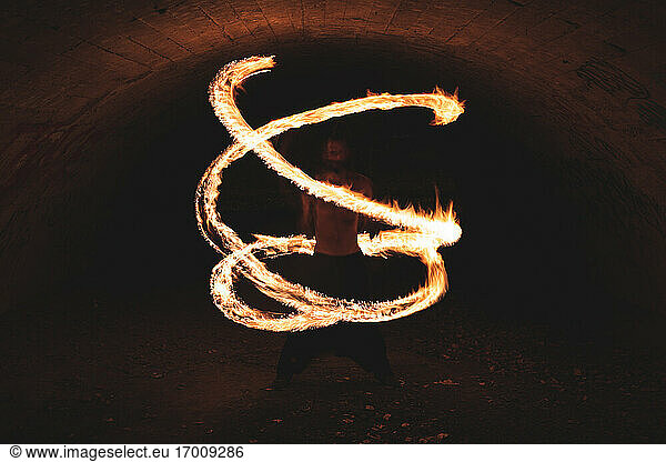 Junger Mann zeigt Feuerkunst im Tunnel