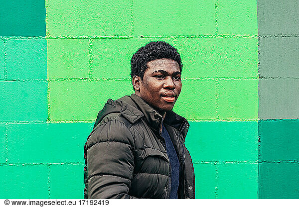 Junger schwarzer afroamerikanischer amerikanischer Junge auf grünem Wandhintergrund.
