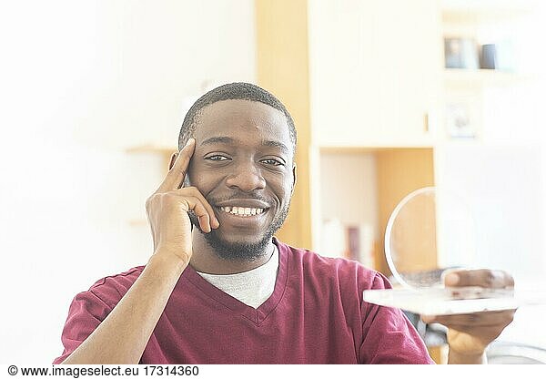 Junger schwarzer Mann mit Probe überdenkt eine Vision oder Innovation im Büro  Freiburg  Baden-Württemberg  Deutschland  Europa