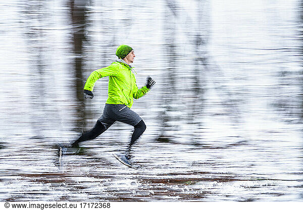 Junger Sportler  der bei kalten Temperaturen im Wald rennt