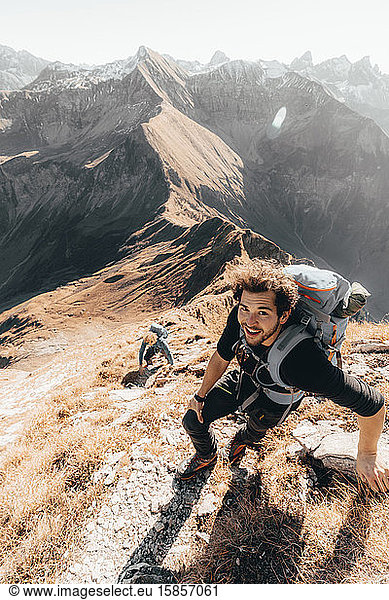 Junger Wanderer erklimmt einen steilen Bergpfad vor den Bergen