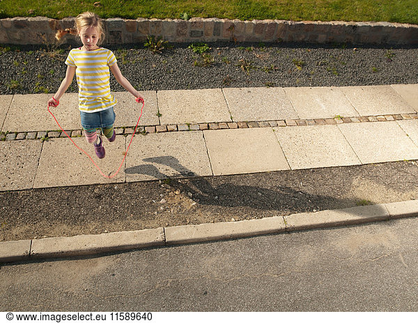 Junges Mädchen hüpft auf dem Bürgersteig