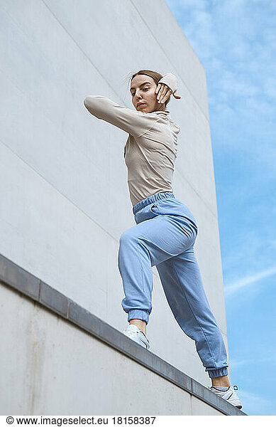 Junges Mädchen in einer blauen Hose streckt sich und tanzt gegen den blauen Himmel