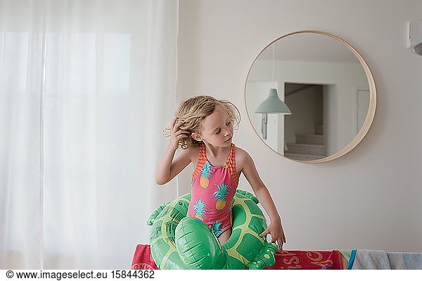junges Mädchen mit aufblasbarem Ring und Badeanzug stand zu Hause