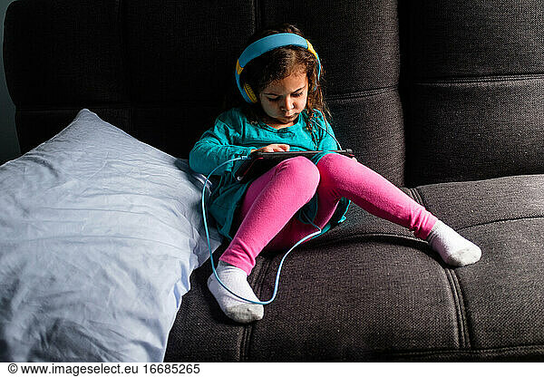Junges Mädchen spielt iPad-Spiel auf einer Couch
